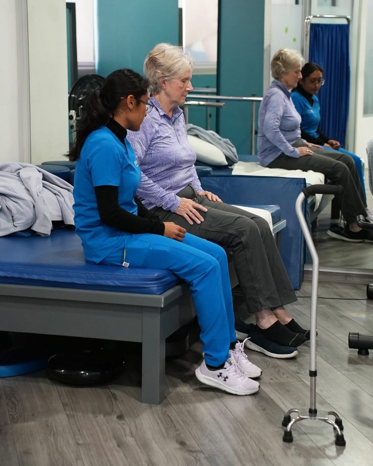 Fisioterapeuta acompañando a una paciente adulta mayor en su sesión de rehabilitación